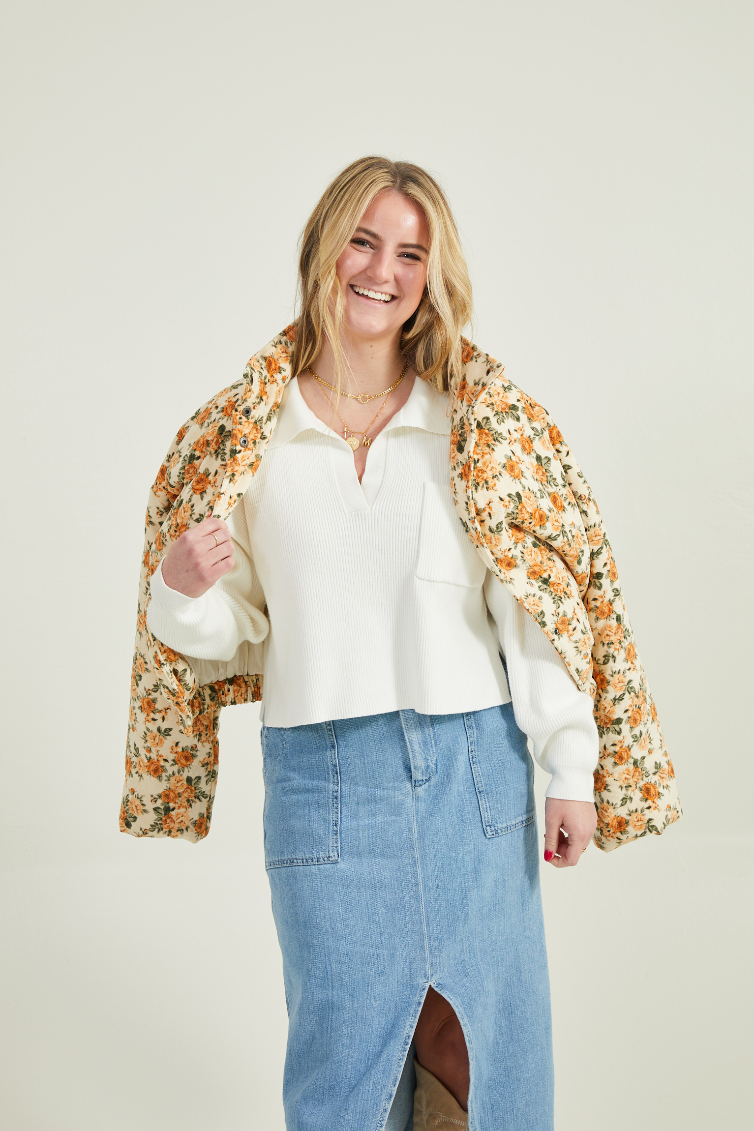 woman wearing a denim skirt and floral puffer jacket